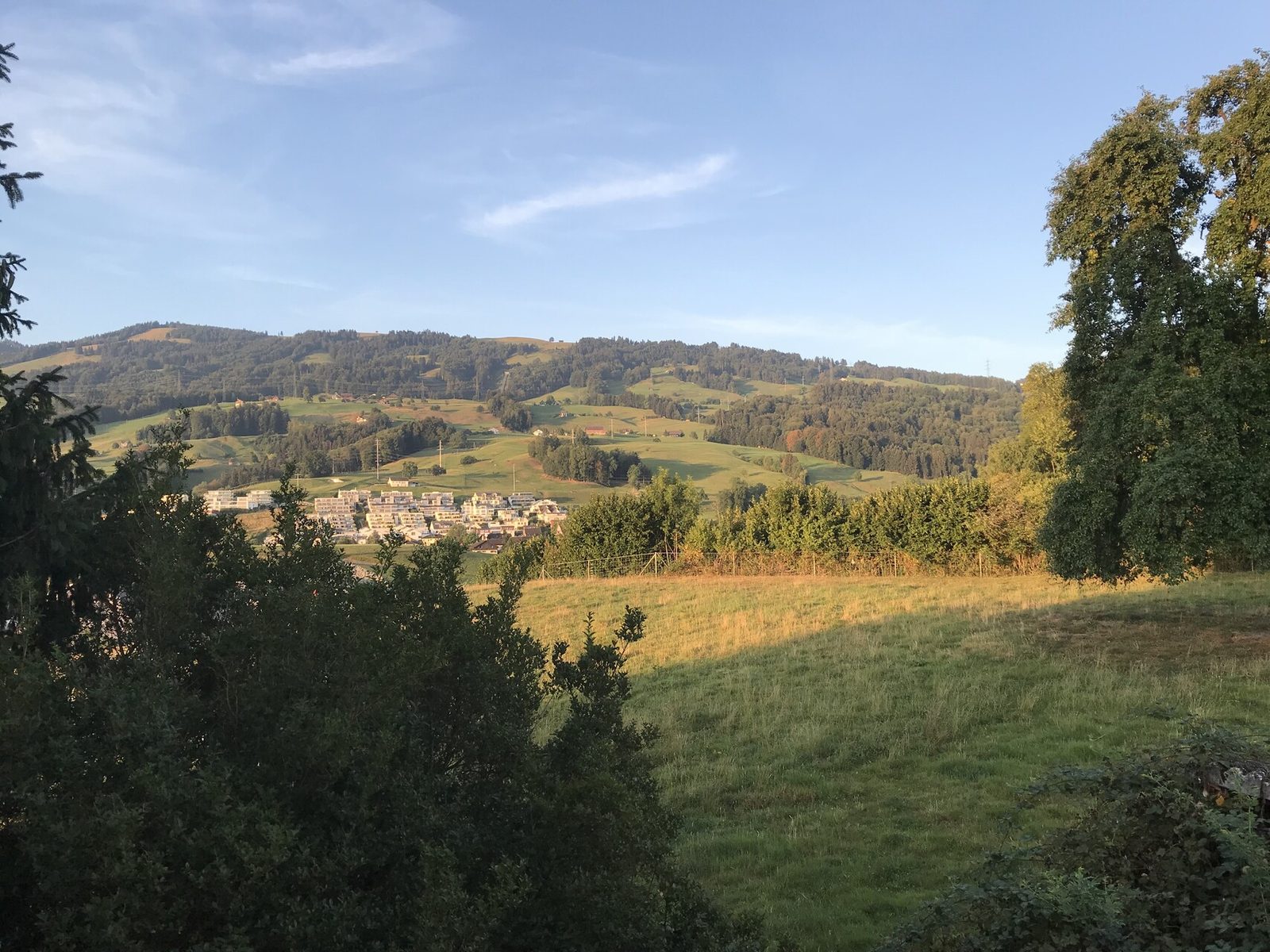 Rückwärtiger Blick über Grünraum und die ansteigende Hanglandschaft